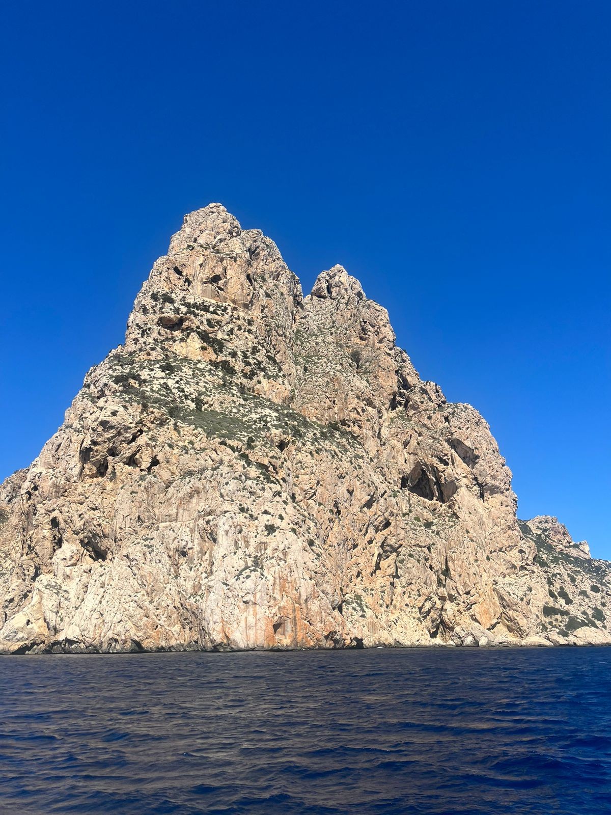 Rocky islet seen from the sea under a blue sky