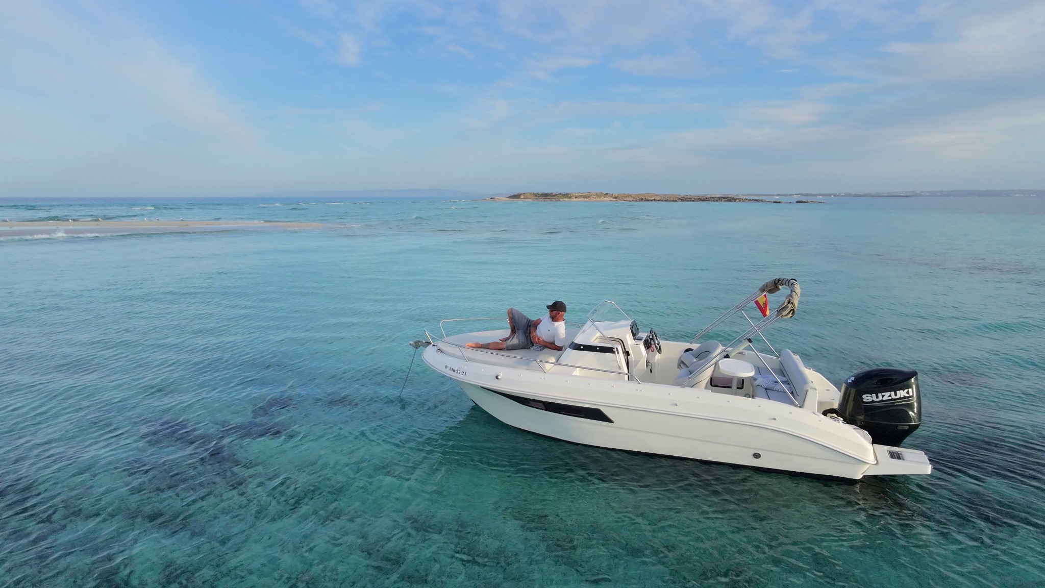 Buena Proa anchored in clear waters next to a beach