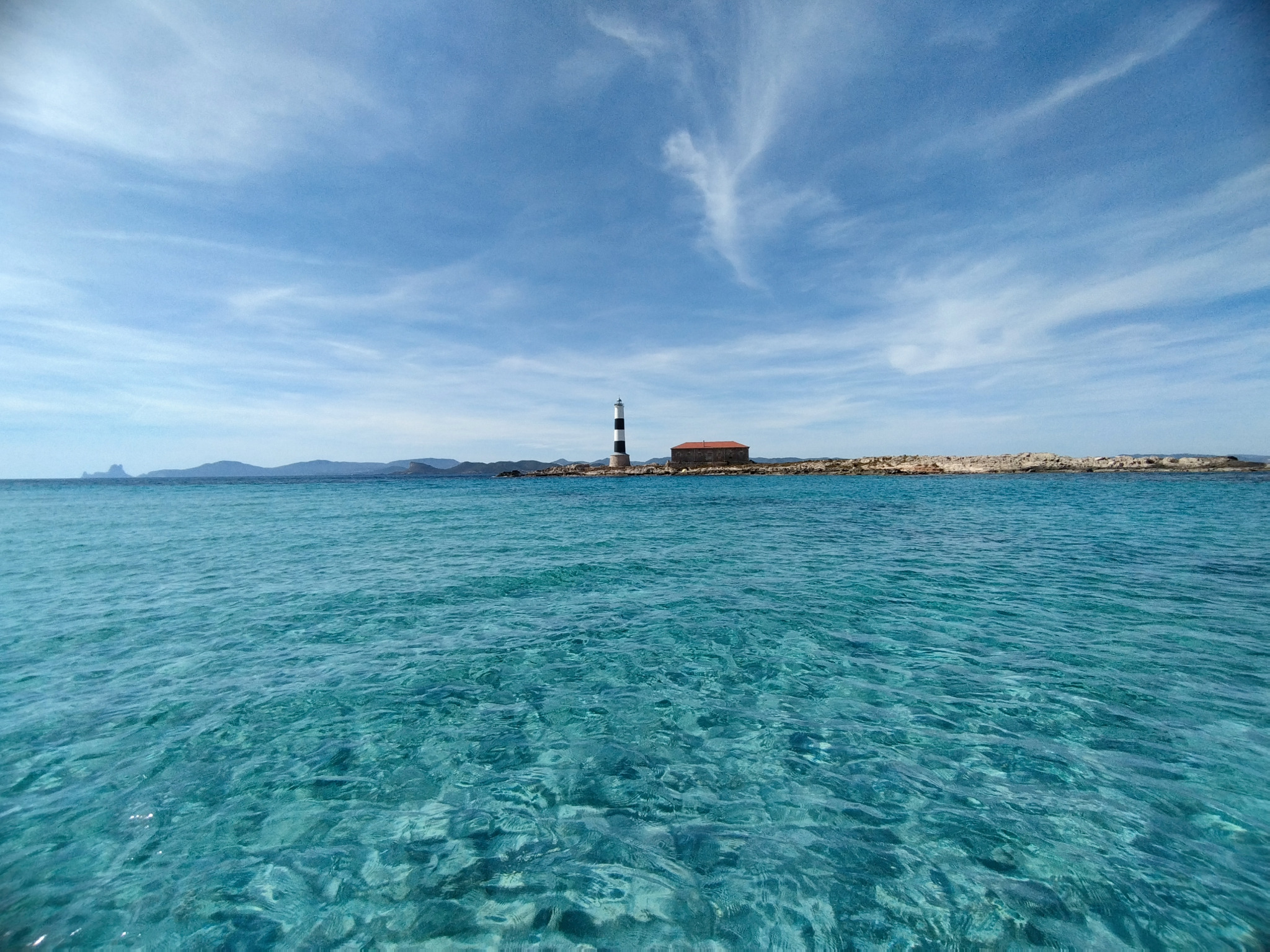 Lighthouse and crystal-clear waters on the Buena Proa route