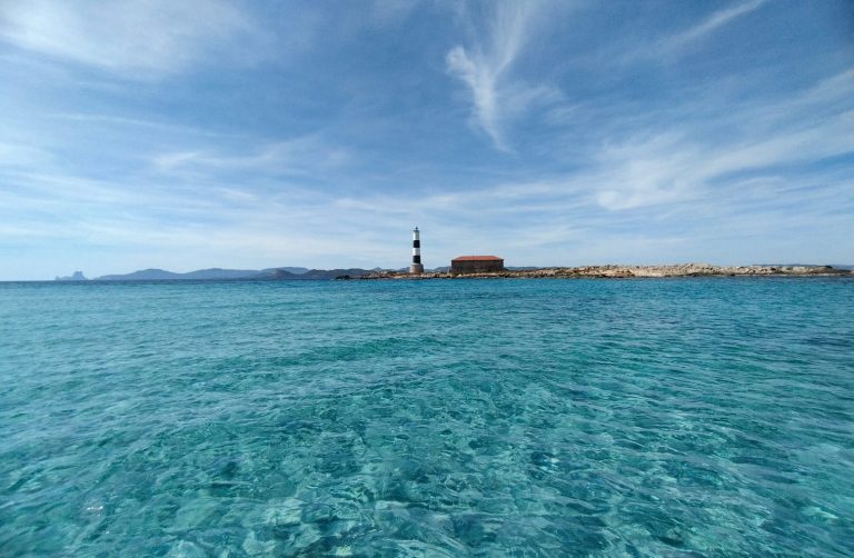 Foto barco faro Formentera. Precios alquiler Aguas cristalinas con Ibiza y un faro al fondo